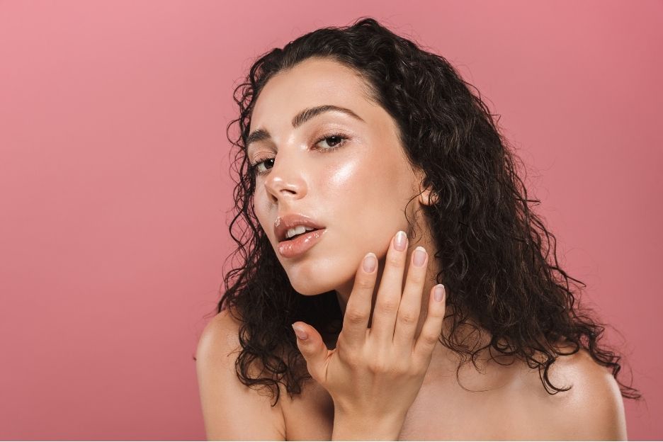 Woman examining her skin for balanced pH levels, highlighting healthy skincare routines.